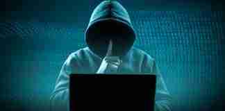 Faceless hooded hacker showing silence gesture. Cyber attack, system breaking and malware.